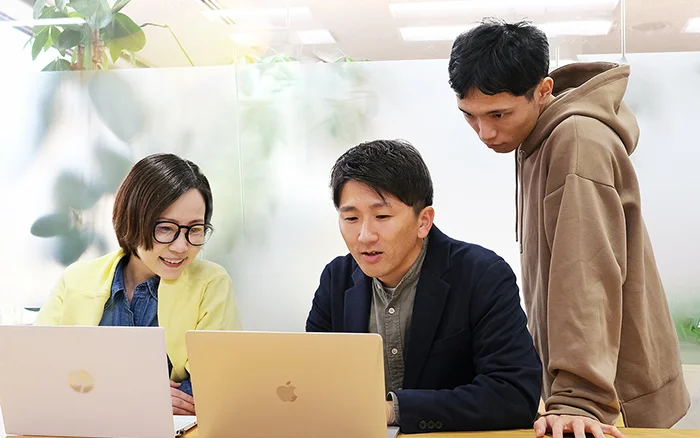 写真　パソコンを前に社員四人が談笑しながら会議する様子