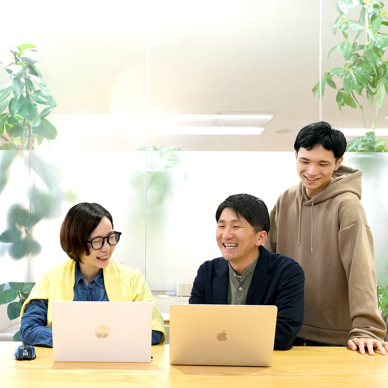 写真　パソコンを前に社員四名が談笑しながら会議する様子